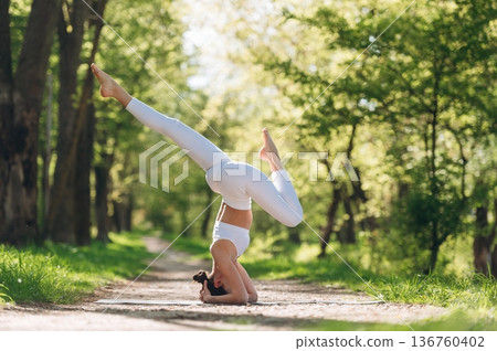 Doing headstand. Beautiful fitness yoga woman is outdoors, amazing nature Doing headstand. Beautiful fitness yoga woman is outdoors, amazing nature 136760402