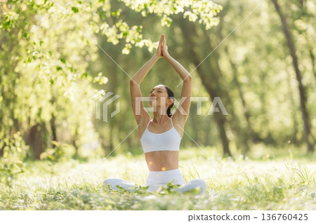 On the grass, sitting. Beautiful fitness yoga woman is outdoors, amazing nature On the grass, sitting. Beautiful fitness yoga woman is outdoors, amazing nature 136760425