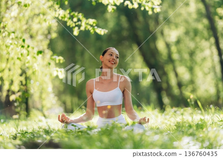 Lotus pose, sitting on the grass. Beautiful fitness yoga woman is outdoors, amazing nature Lotus pose, sitting on the grass. Beautiful fitness yoga woman is outdoors, amazing nature 136760435