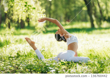 Spine stretching. Beautiful fitness yoga woman is outdoors, amazing nature Spine stretching. Beautiful fitness yoga woman is outdoors, amazing nature 136760442