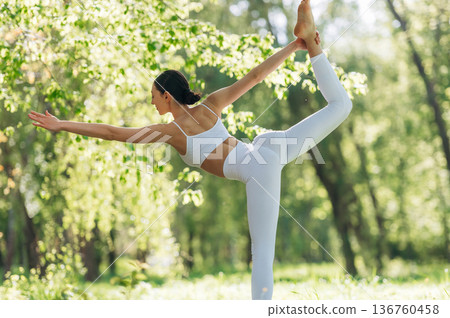 Practicing the asana. Beautiful fitness yoga woman is outdoors, amazing nature Practicing the asana. Beautiful fitness yoga woman is outdoors, amazing nature 136760458