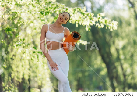 Ready for practice, standing and holding mat. Beautiful fitness yoga woman is outdoors, amazing nature 136760465