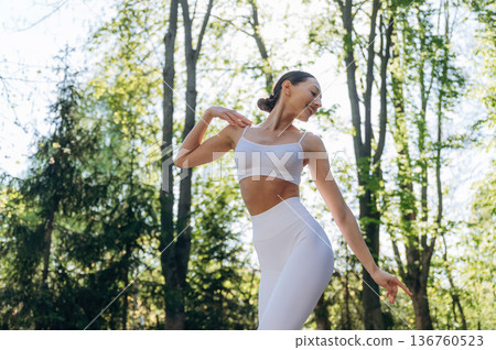 Standing in the forest. Beautiful fitness yoga woman is outdoors, amazing nature Standing in the forest. Beautiful fitness yoga woman is outdoors, amazing nature 136760523