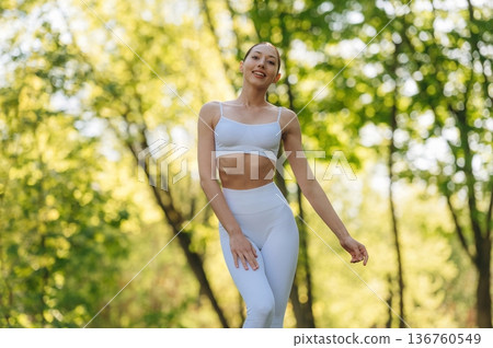 In fitness clothes. Beautiful yoga woman is outdoors, amazing nature In fitness clothes. Beautiful yoga woman is outdoors, amazing nature 136760549