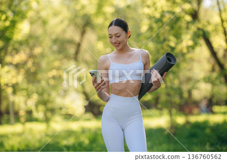 Using phone. Beautiful fitness yoga woman is outdoors, amazing nature Using phone. Beautiful fitness yoga woman is outdoors, amazing nature 136760562
