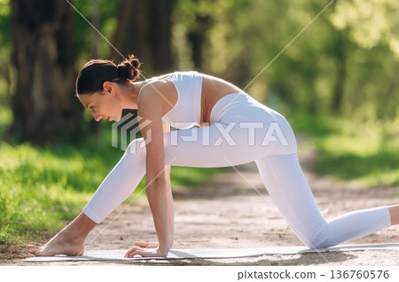 Park pathway, doing exercise. Beautiful fitness yoga woman is outdoors, amazing nature Park pathway, doing exercise. Beautiful fitness yoga woman is outdoors, amazing nature 136760576