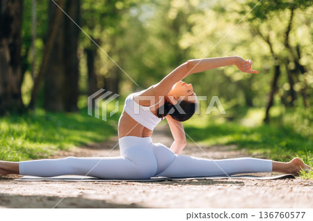 Park pathway, doing exercise. Beautiful fitness yoga woman is outdoors, amazing nature Park pathway, doing exercise. Beautiful fitness yoga woman is outdoors, amazing nature 136760577