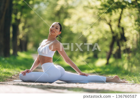 Legs are stretched, sitting. Beautiful fitness yoga woman is outdoors, amazing nature Legs are stretched, sitting. Beautiful fitness yoga woman is outdoors, amazing nature 136760587