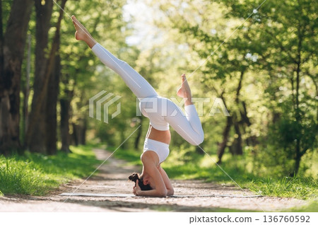 Doing headstand. Beautiful fitness yoga woman is outdoors, amazing nature Doing headstand. Beautiful fitness yoga woman is outdoors, amazing nature 136760592