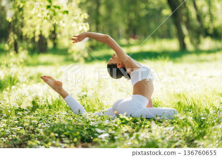 Spine stretching. Beautiful fitness yoga woman is outdoors, amazing nature 136760655