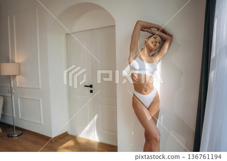By the wall and near door. Young woman in fitness clothes is in the room By the wall and near door. Young woman in fitness clothes is in the room 136761194
