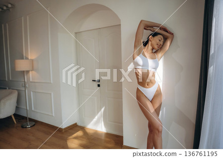 By the wall and near door. Young woman in fitness clothes is in the room By the wall and near door. Young woman in fitness clothes is in the room 136761195