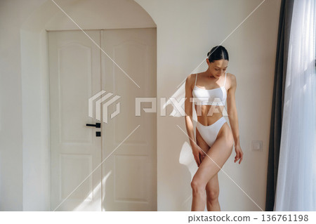 Beautiful woman is standing and posing. Young female in fitness clothes is in the room 136761198