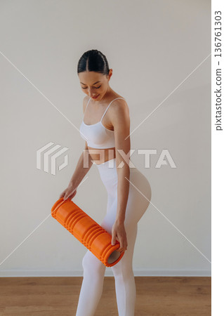 Getting ready for practice, with roll. Young woman in sportive clothes is against the wall 136761303