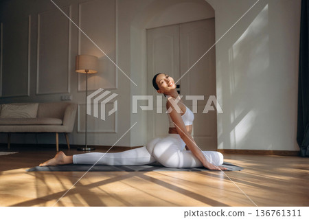 Stretching the legs. Young woman in fitness clothes is in the room Stretching the legs. Young woman in fitness clothes is in the room 136761311