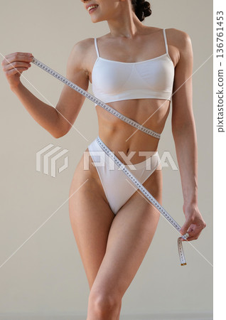 Diet conception. Measuring the waist. Close up view of woman that is in fitness clothes Diet conception. Measuring the waist. Close up view of woman that is in fitness clothes 136761453