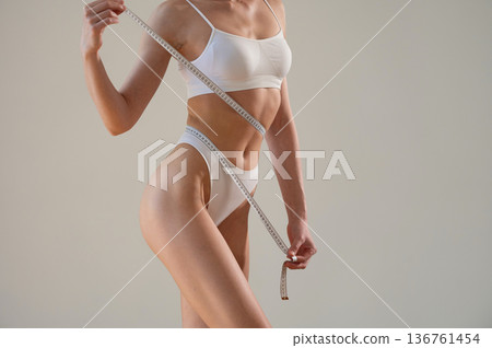 Focused view, measuring the waist. Close up view of woman that is in fitness clothes 136761454