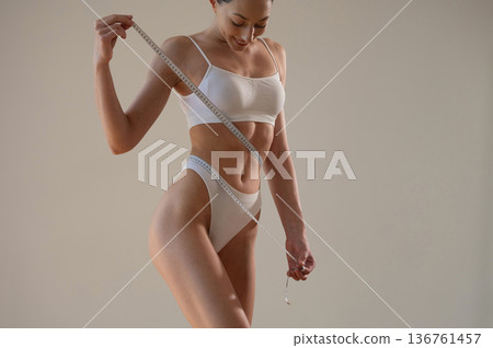 Successful weight loss. Young woman in sportive clothes is against the wall 136761457