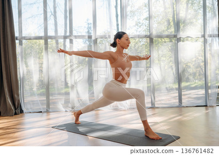 Asana exercise. Young woman in fitness clothes is in the room 136761482