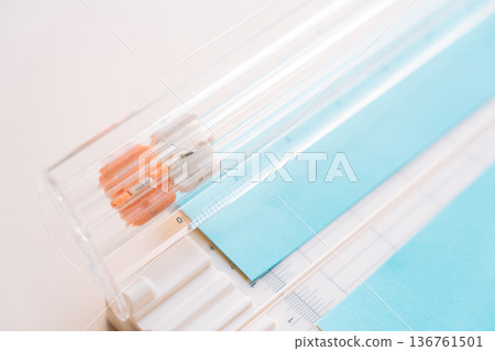 Close up of paper cutter with blue cardstock and measurement grid, scrapbooking and paper craft concept Close up of paper cutter with blue cardstock and measurement grid, scrapbooking and paper craft concept 136761501