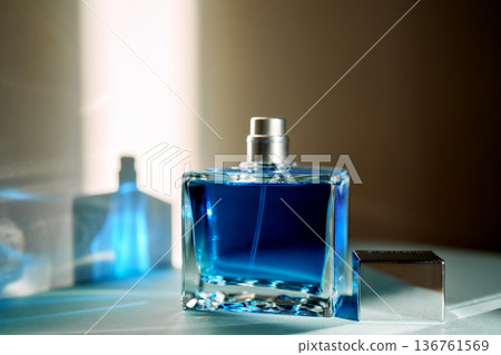 Blue perfume bottle reflecting light on a table Blue perfume bottle reflecting light on a table 136761569