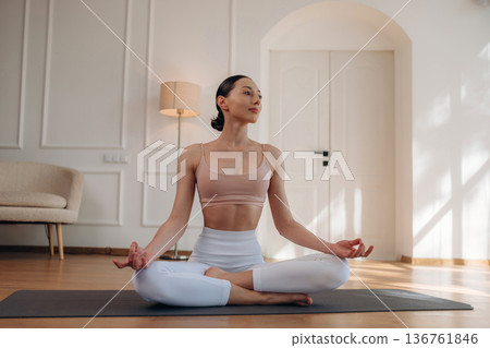 Modern interior, on the floor. Young woman in fitness clothes is in the room Modern interior, on the floor. Young woman in fitness clothes is in the room 136761846