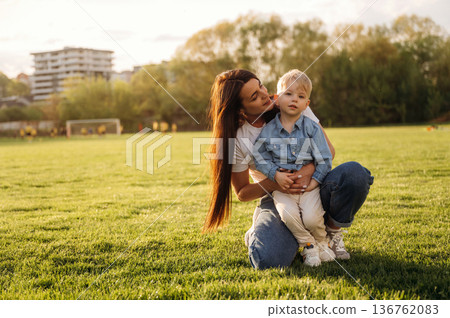 Warm sunlight. Mother and son are together on the summer field Warm sunlight. Mother and son are together on the summer field 136762083