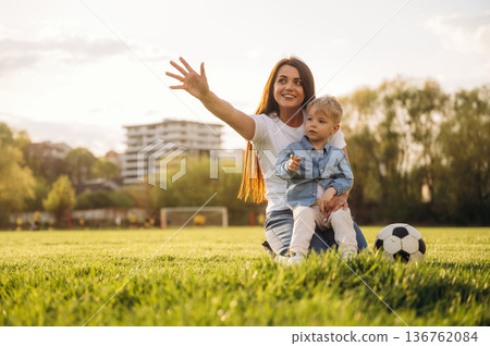 Looking far away. Mother and son are together on the summer field Looking far away. Mother and son are together on the summer field 136762084