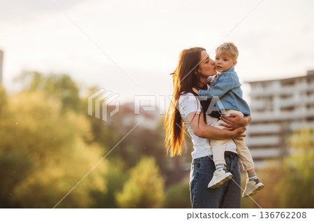 Warm sunlight. Mother and son are together on the summer field Warm sunlight. Mother and son are together on the summer field 136762208
