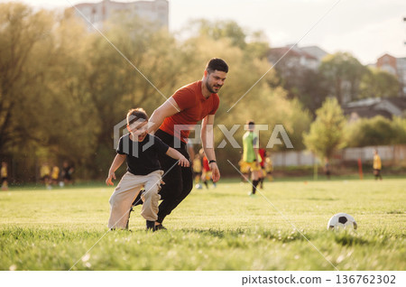 Learning how to play soccer. Father and son are having fun outdoors Learning how to play soccer. Father and son are having fun outdoors 136762302
