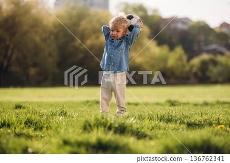 Kid is with soccer ball. Little boy is having fun on the field outdoors 136762341