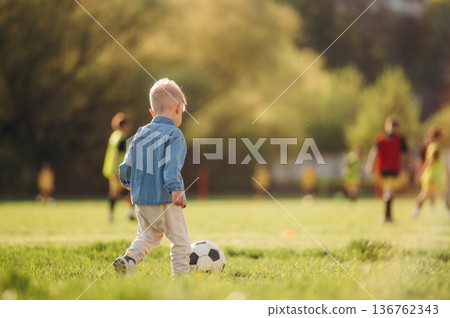 Kid is with soccer ball. Little boy is having fun on the field outdoors Kid is with soccer ball. Little boy is having fun on the field outdoors 136762343