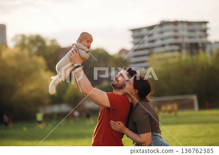 Positive facial expression. Happy couple parents are with little baby outdoors Positive facial expression. Happy couple parents are with little baby outdoors 136762385