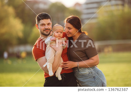 Positive facial expression. Happy couple parents are with little baby outdoors 136762387