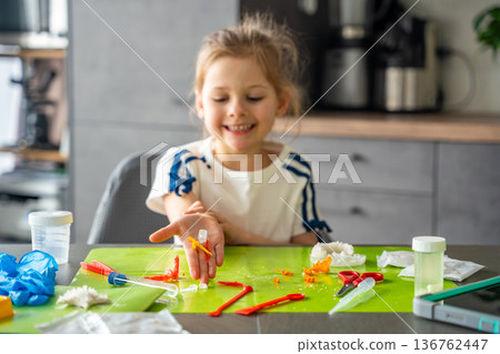 Child hand holding colorful crystals of different shapes at home science table. Crystal growing experiment results and hands on STEM discovery through practical learning. 136762447