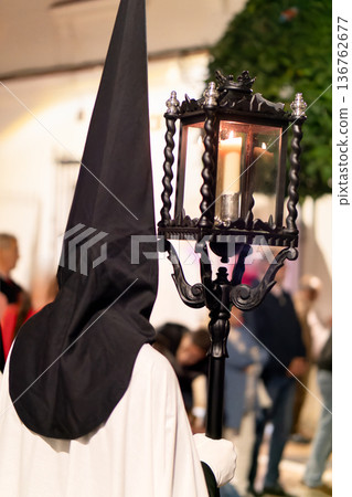 Nazareno holding a traditional lantern during a solemn Holy Week procession at night 136762677