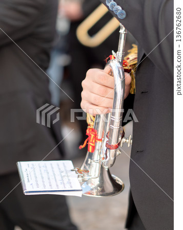 Close up of a musician holding a silver trumpet with sheet music during parade Close up of a musician holding a silver trumpet with sheet music during parade 136762680