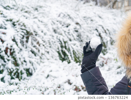 Snowball in hand, snowfall in the city. Outdoor family games in winter, climate change concept Snowball in hand, snowfall in the city. Outdoor family games in winter, climate change concept 136763224