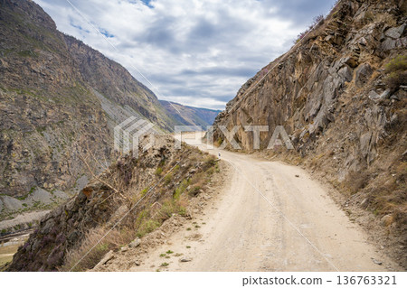Gravel road winding through Katu Yaryk pass in Altai mountains Russia Mountain route connecting remote valley with highland plateau 136763321