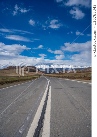 Asphalt road leading to snow-covered Akturu ridge in Kurai steppe valley Altai, Russia Asphalt road leading to snow-covered Akturu ridge in Kurai steppe valley Altai, Russia 136763342