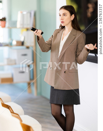Girl teacher speaker with remote control during lecture Girl teacher speaker with remote control during lecture 136763357