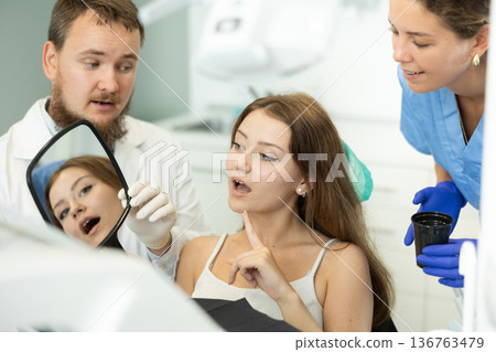 Woman at a dentist appointment with a man looking in the mirror Woman at a dentist appointment with a man looking in the mirror 136763479