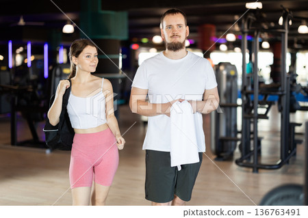 Girl and man visitors of gym chat after workout Girl and man visitors of gym chat after workout 136763491
