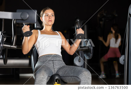Young woman training her arms on machine Young woman training her arms on machine 136763500