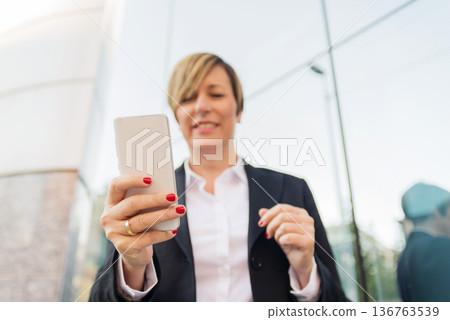 Business woman using smartphone outdoors 136763539