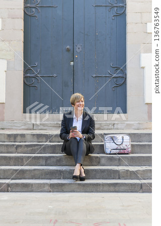 Businesswoman sitting on steps with coffee cup 136763549