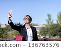 Businesswoman taking selfie on sunny city bridge 136763576