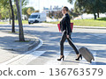 Businesswoman crossing street with suitcase 136763579