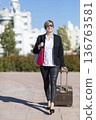 Businesswoman walking with suitcase in city 136763581