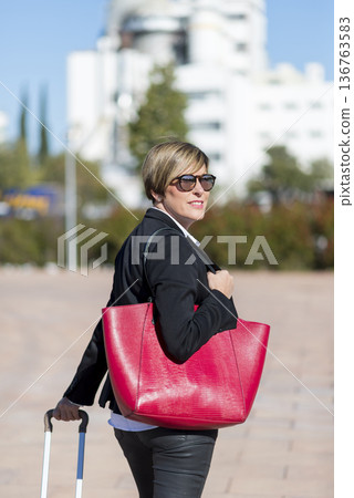 Businesswoman with red bag walking in city Businesswoman with red bag walking in city 136763583